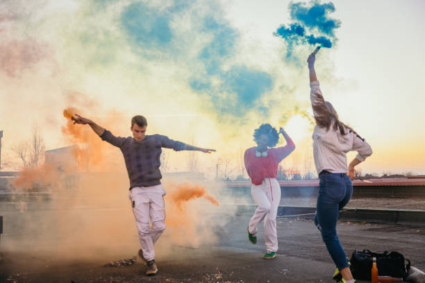 istock Young man and women holding multi colored flares on roof 1372340898