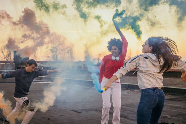 istock Young man and women holding multi colored flares on roof 1372340962