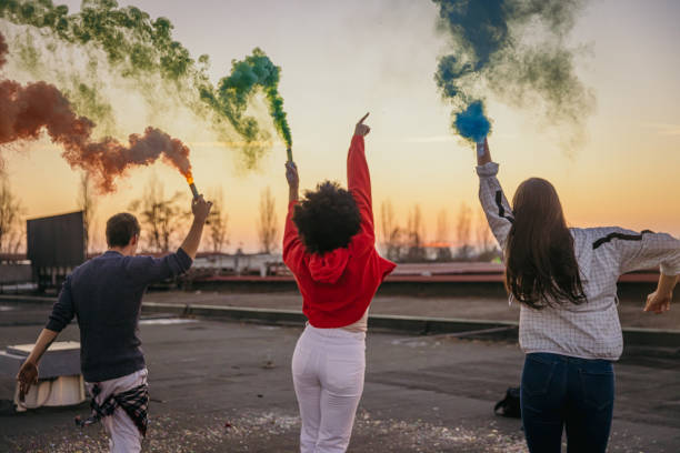 istock Young man and women holding multi colored flares on roof 1372341082