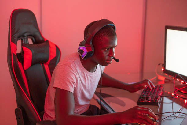 istock Young black male gamer playing at station using desktop computer and laptop 1372341631