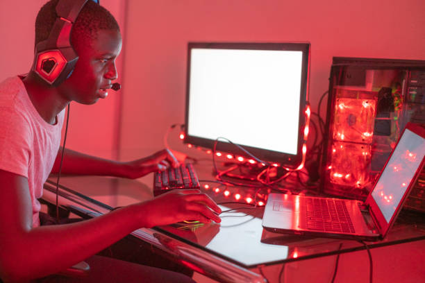 istock Young black male gamer playing at station using desktop computer and laptop 1372341643