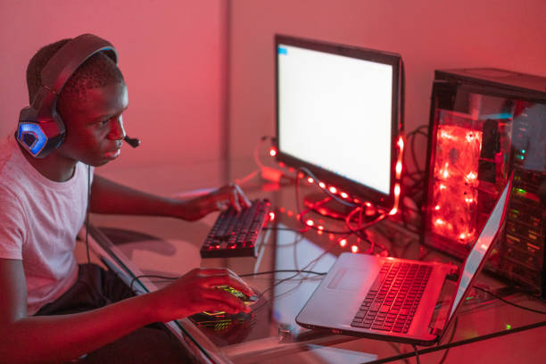 istock Young black male gamer playing at station using desktop computer and laptop 1372341646