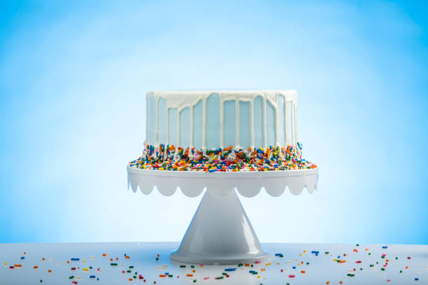 istock Blue Birthday Cake with Sprinkles on a White Cake Plate and Blue Background 1372341782
