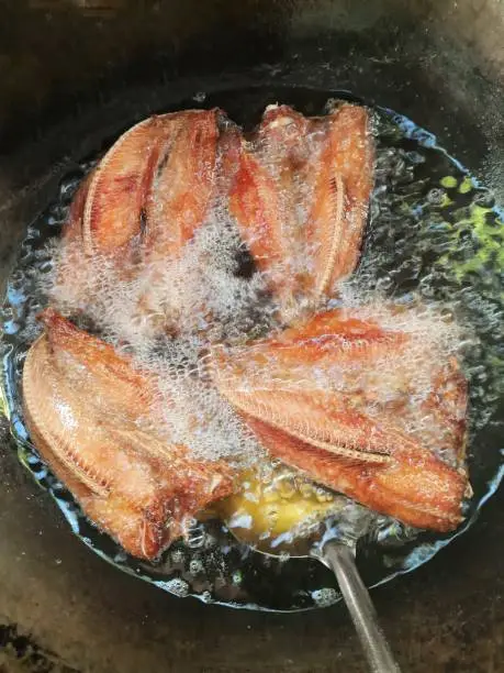 Frying Dried Snakehead Fish in cooking pan - food preparation.