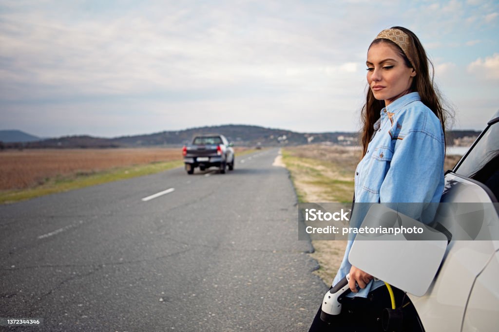 Desperate woman with electric car without power in battery is looking for help Electric Car Stock Photo