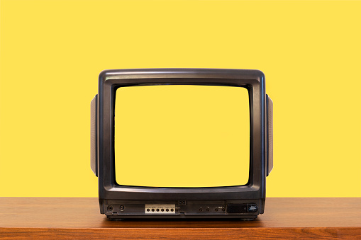 Yellow color background, vintage old television on wood table with blank yellow screen.