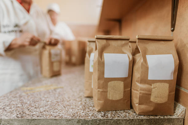Freshly filled flour brown paper packages with blank labels on table in mill