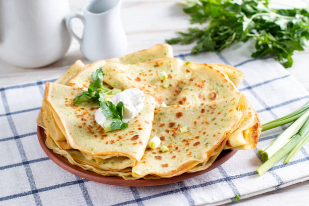 a stack of pancakes with fresh dill and onions on a white plate. traditional russian pancakes for maslenitsa. - baking flour ingredient animal egg imagens e fotografias de stock