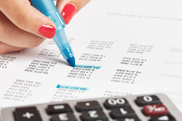 Close-up of female accountant or auditor's hand working on corporate financial figures.
