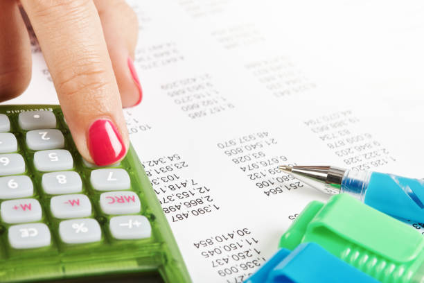 Close-up of female accountant or auditor's hand working on corporate financial figures.