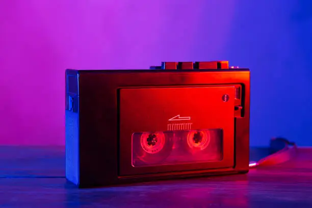 Vintage cassette tape player in neon light. 90s advertisement style. Disco party nostalgy concept