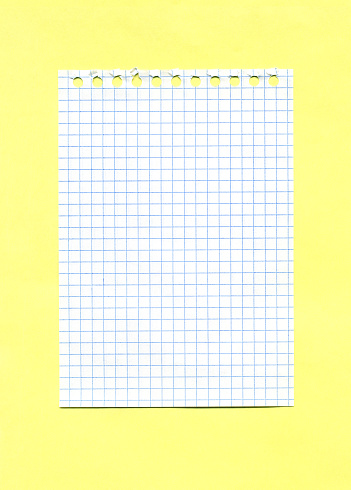 Checked paper sheet torn out of a spiral notebook isolated on yellow background. Minimalistic mockup with copy space.