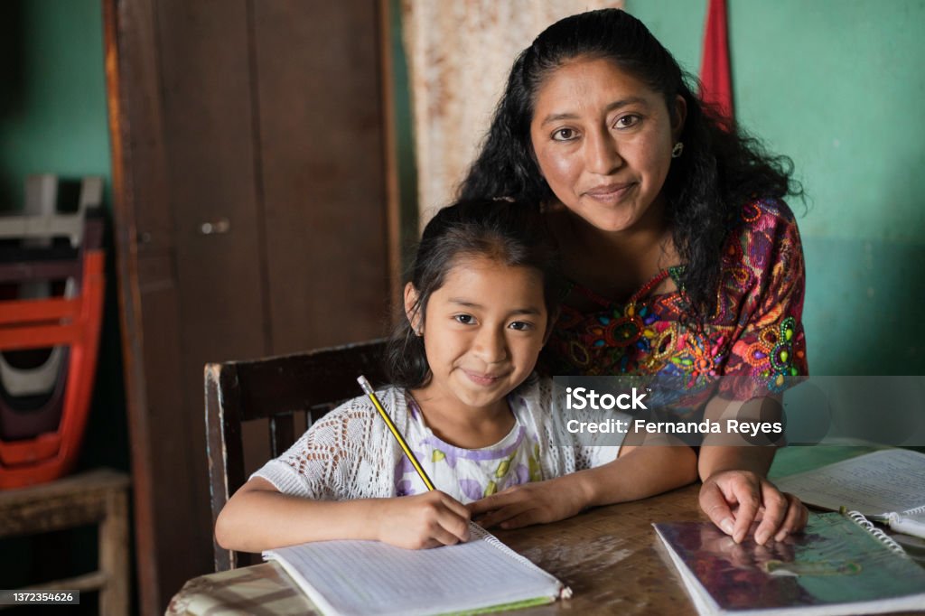 Hispanic mom helping her little daughter do her homework - Mom teaching her daughter to read and write at home - Mayan family at home Latin American and Hispanic Ethnicity Stock Photo