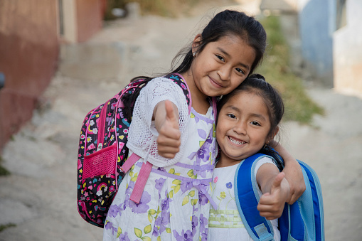 Hispanic girls ready to go to school in rural area - Latin sisters on their way to school - Happy Mayan girls with thumbs up