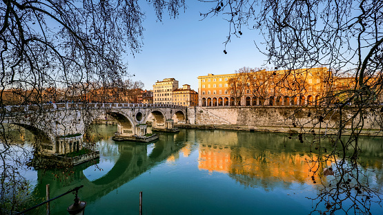 A suggestive sunset view along the bank of the Tiber river in the Trastevere district, in the historic heart of Rome, with the Ponte Sisto on the left. The Ponte Sisto (Sixtus Bridge), one of the oldest bridges in Rome, was rebuilt in 1473 during the pontificate of Pope Sixtus IV using the structure of the Roman era Pons Aurelius bridge to connect Trastevere with the center of the Eternal City. Trastevere is an iconic district of Rome for the presence of artistic and historical treasures, for the archaeological remains of Ancient Rome and for the numerous Romanesque and Baroque churches. Among beautiful squares and suggestive alleys to be explored freely, you can find typical restaurants, pubs, small artisan shops and scenes of everyday life and the original Roman soul. In 1980 the historic center of Rome was declared a World Heritage Site by Unesco. Super wide angle image in 16:9 and high definition format.