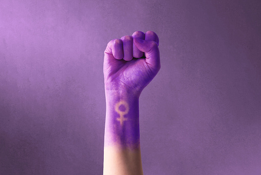 Levantó el puño morado de una mujer por el día internacional de la mujer y el movimiento feminista. 8 de marzo por el feminismo, la independencia, la libertad, el empoderamiento y el activismo por los derechos de las mujeres photo