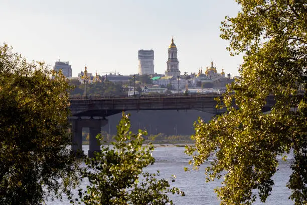 Photo of Bright evening cityscape of the big city on the hill over wide river Dnipro in awesome bright sunset in Kyiv, Ukraine. View at Kyiv-Pechersk Lavra National Reserve.