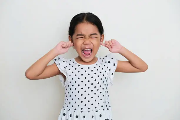 Photo of Asian kid screaming loud and closed her ears with finger