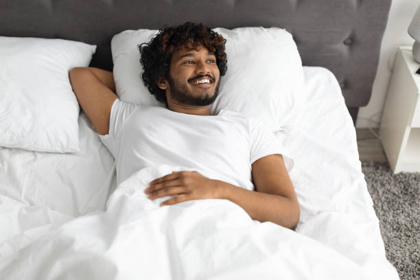 istock Happy indian guy enjoying good morning in bed 1372361216