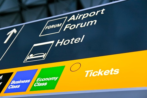 Illuminated directional sign with pictograms at the airport with information where to find the hotels, the airport lobby and ticket counters.