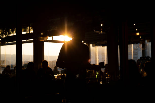 istock Waiter in silhouette carrying the tray with drinks 1372364304