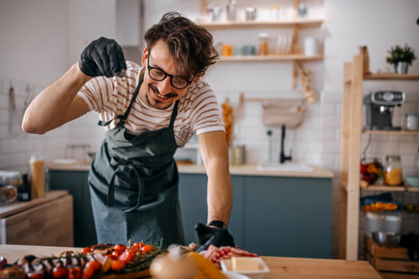 istock Happy man sprinkling pepper on steak in kitchen 1372364547