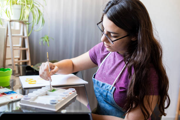 istock Young woman working on a painting 1372365795