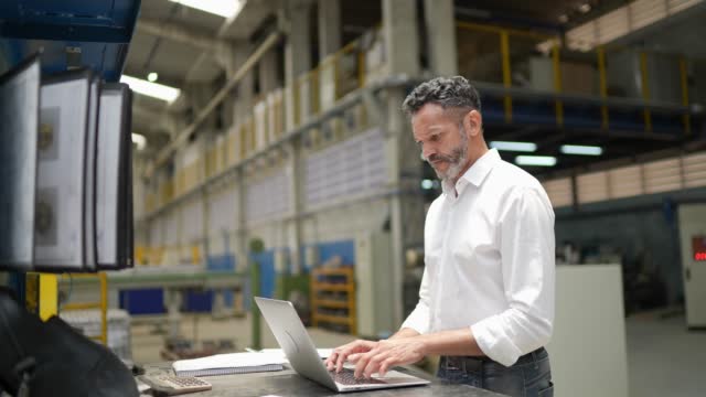 Mature man using laptop in a factory/industry