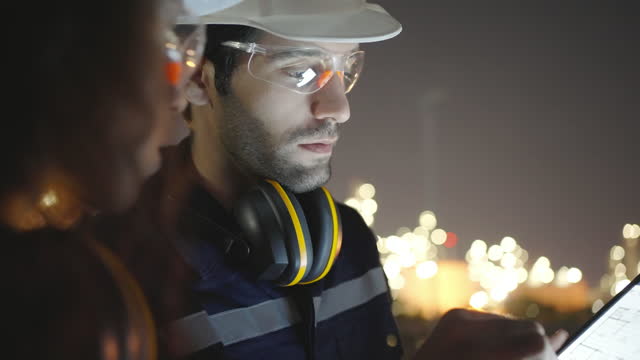 Caucasians or middle east engineer checking and work discussion at oil refinery at night time.