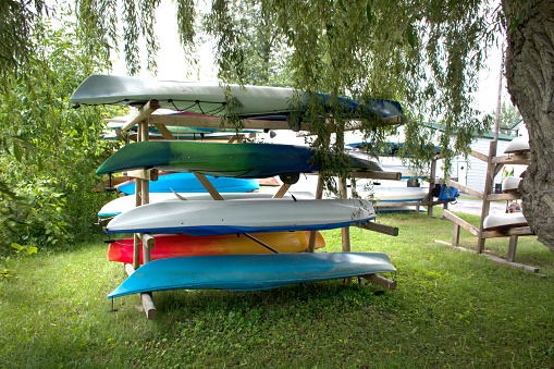 Multicolored colorful kayaks stored upside down on outdoor wood vertical storage rack. High quality photo