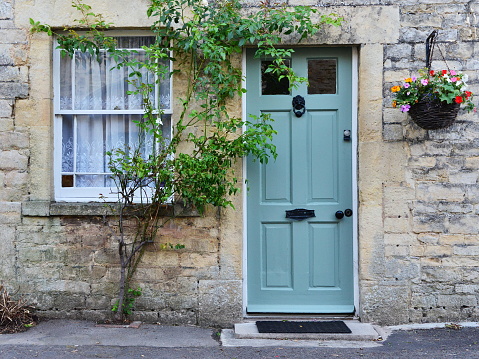 Exterior of a traditional English cottage house with front door, window and flowers