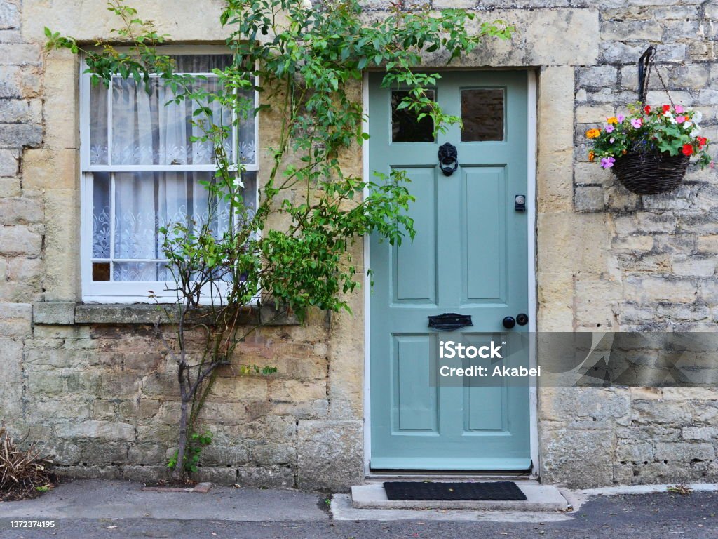 Traditional Cottage House Exterior of a traditional English cottage house with front door, window and flowers Door Stock Photo