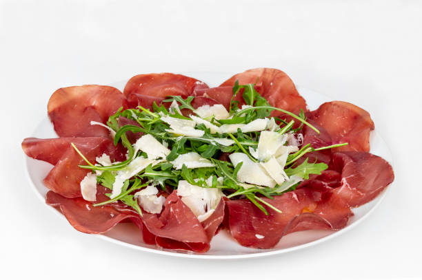 piatto di bresaola con rucola e parmigiano in primo piano su fondo bianco. cibo tipico italiano. - bresaola foto e immagini stock