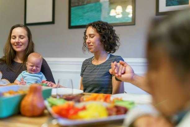 istock Extended family saying prayer before holiday meal at dinner table 1372375182