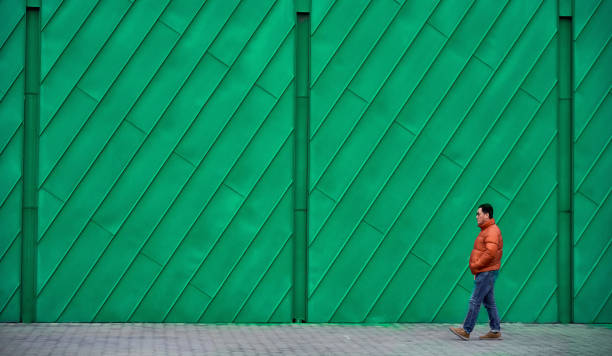 istock A man in a red coat walked past the green wall 1372375192