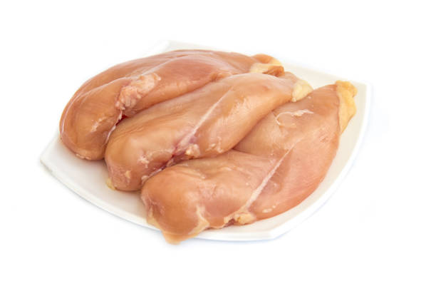 Boiled chicken breast fillet only is in a white plate on a white background. View from above. Vertical orientation. High quality photo.