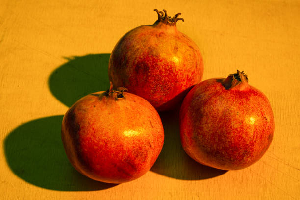 Three ripe pomegranates on the wooden table.