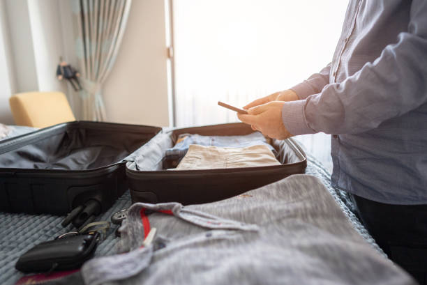 istock Close up businessman using phone while preparing for trip in the bedroom. 1372379435