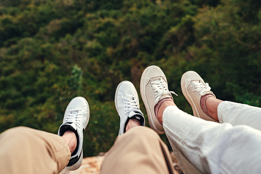 Closeup shot of woman and man feet on cliff relaxing mountains, Love and travel happy emotions Lifestyle concept.