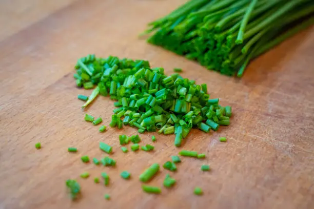 freshly cut green chives on wooden board to decorate main dish