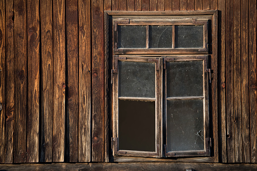 Sunja, Croatia, 05,04,2021: Rustic style aged window in wooden village rural home wall.