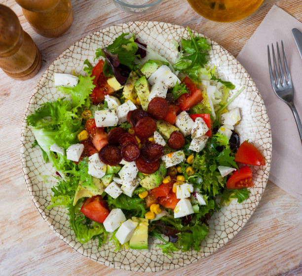 Bright salad with mozzarella, sausages, mix of salads, avocado, tomato and corn