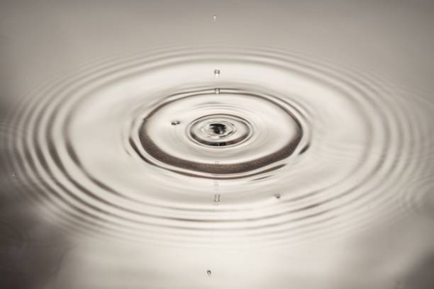 istock Macro view of drops making circles on water surface isolated on background. 1372384558