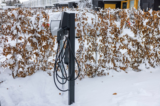 Close up view of pillar with charging cable from an electric vehicle charging station in parking lot on frosty winter day. Sweden.