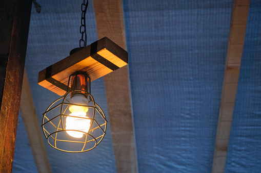 Vintage style lamp, electrical lamp hanging on wooden stab.