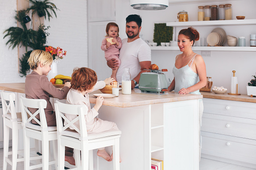 happy family with three kids having breakfast at home in the morning, modern kitchen interior