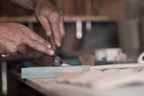 istock Hands carving spoon from wood, working with chisel close up. Wooden workshop. Process of making wooden spoon 1372385139