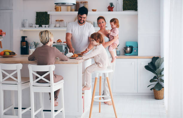 glückliche familie mit drei kindern, die morgens in der küche frühstücken - two parent family indoors home interior domestic kitchen stock-fotos und bilder
