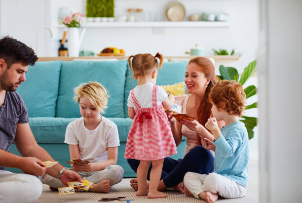 familia feliz jugando juegos de cartas juntos en el suelo de casa - familia con tres hijos fotografías e imágenes de stock