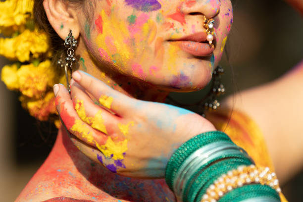 Closeup of young beautiful girl woman lady in indian attire saree with dry organic color or colour or gulal or abeer or Holi powder on her face, Holi festival of color stock photo
